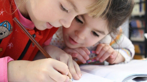Zwei Kindern schreiben in ein Heft